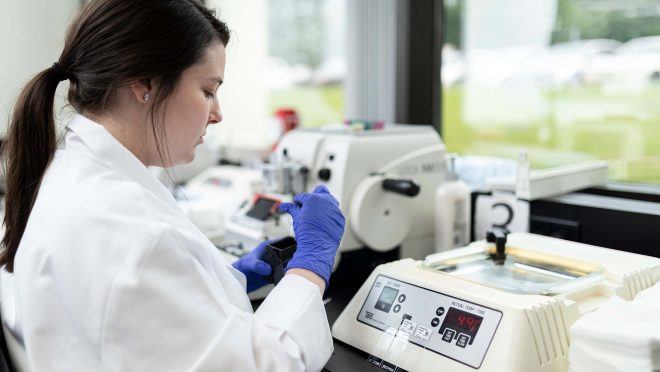 lab technician working at light station processing and cutting biopsies