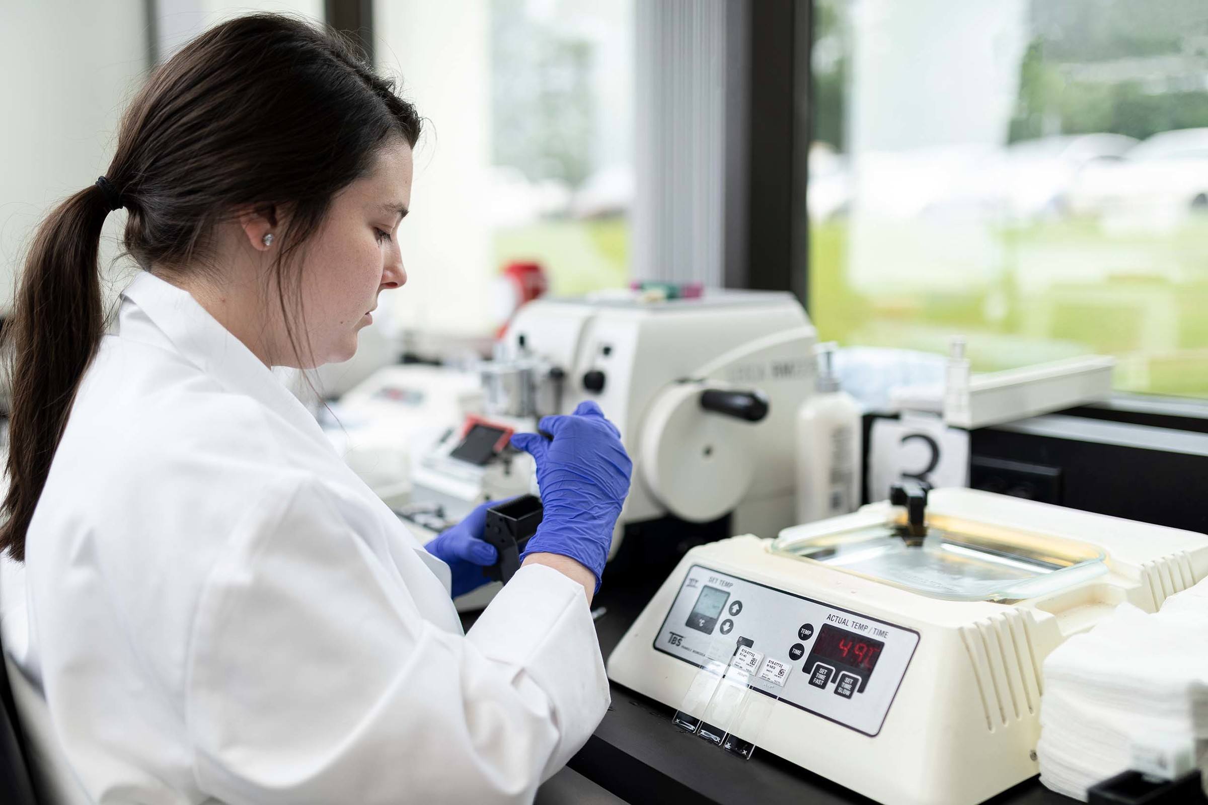 lab technician working at light station processing and cutting biopsies