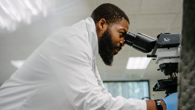 lab member looking at renal biopsy under scope